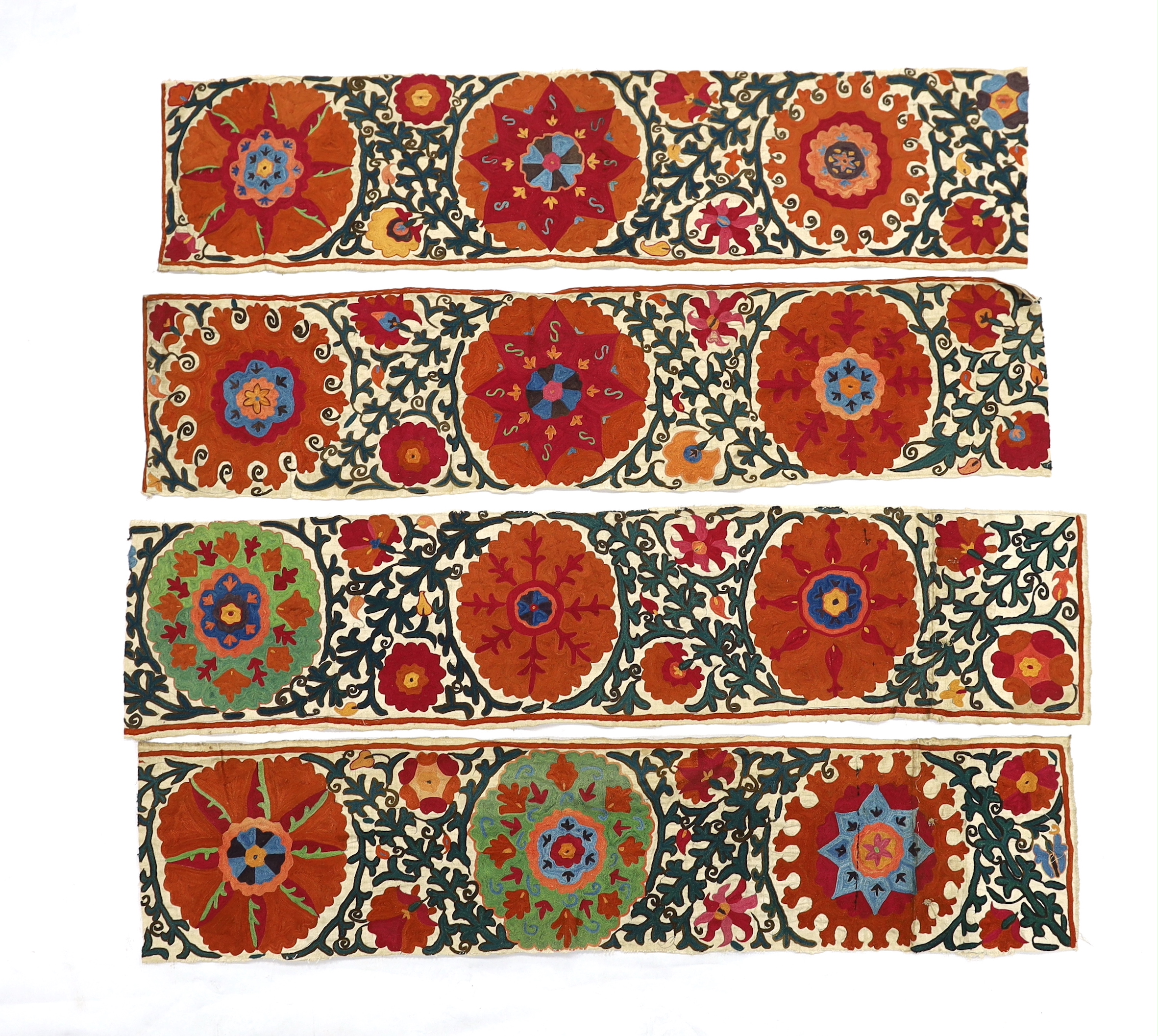 Four early 20th century Uzbek Suzani panels, embroidered with hand dyed silk on thick woven linen, in large brightly multi-coloured symbolic motifs, possibly embroidered for a larger prayer rug or hanging, longest 125cm